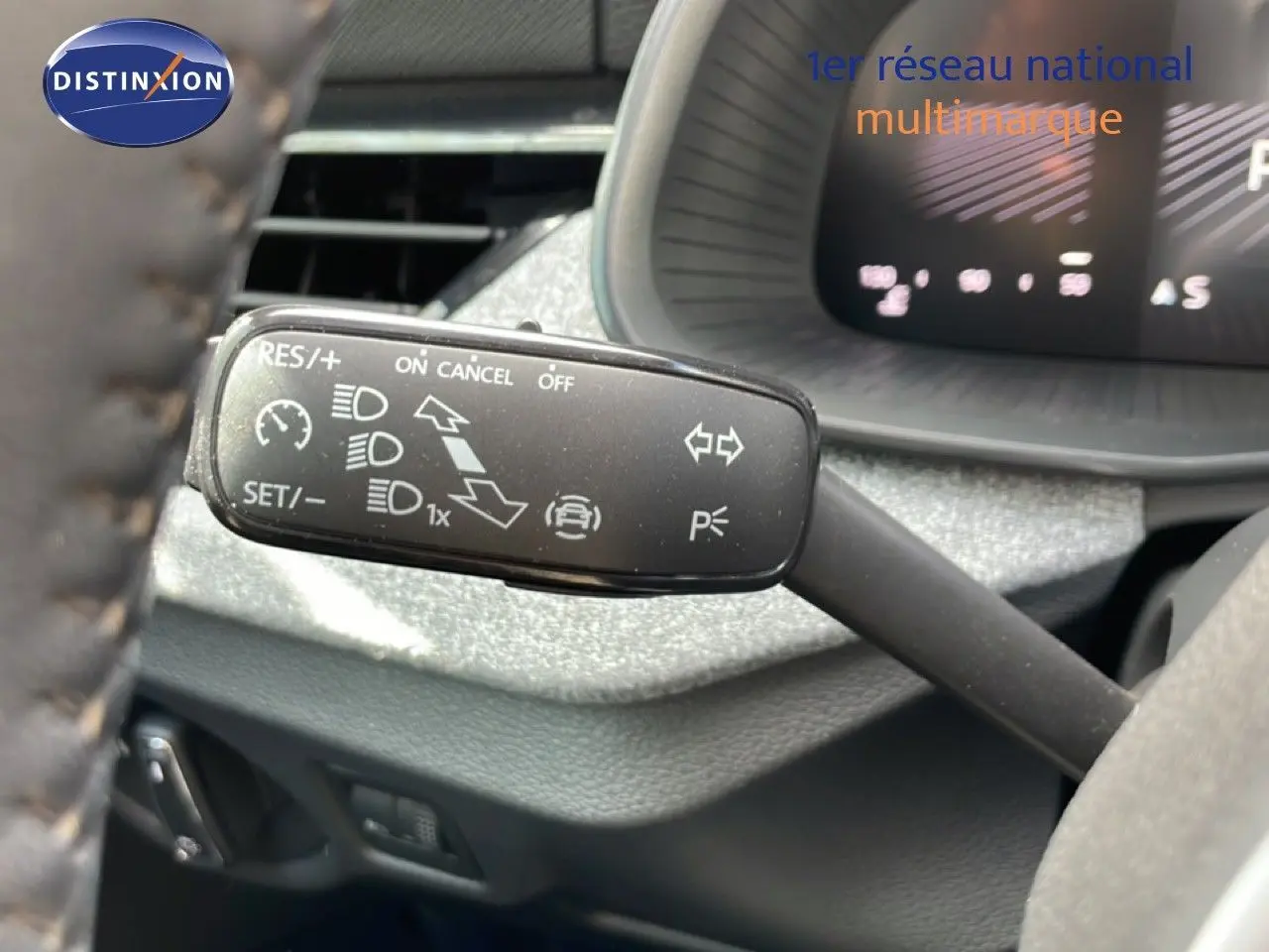 Gros plan sur la commande de régulateur de vitesse à gauche du volant dans l’habitacle gris noir d’une Skoda Scala blanc glacier 2025.