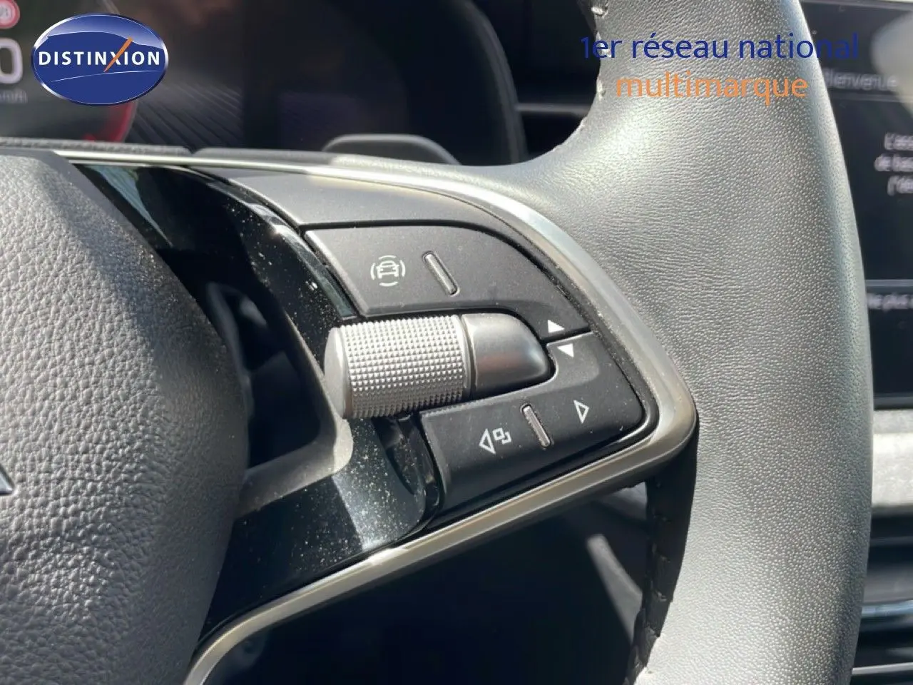 Gros plan sur les commandes gauche du volant gris d'une Skoda Scala blanc glacier, avec molette et boutons multifonctions.