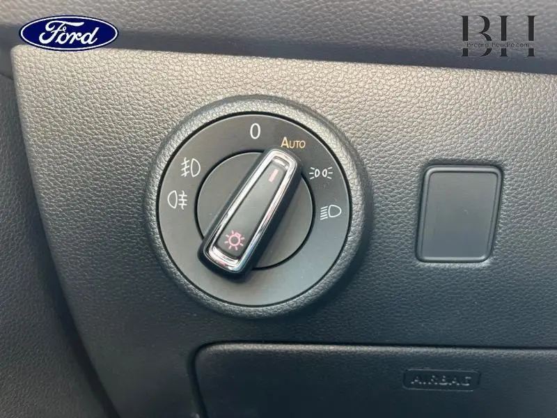 Gros plan sur la molette de réglage des phares d’un SEAT Ateca blanc Nevada Métal, intérieur noir texturé.