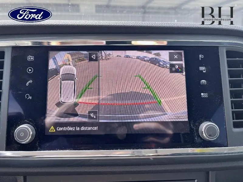 Écran tactile montrant la caméra de recul du SEAT Ateca blanc Nevada, avec lignes de guidage vertes et rouges.