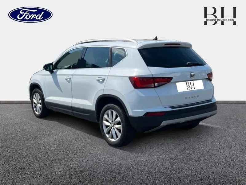 Vue 3/4 arrière droite d'un SEAT Ateca blanc Nevada Métal avec vitres arrière surteintées et jantes alu.