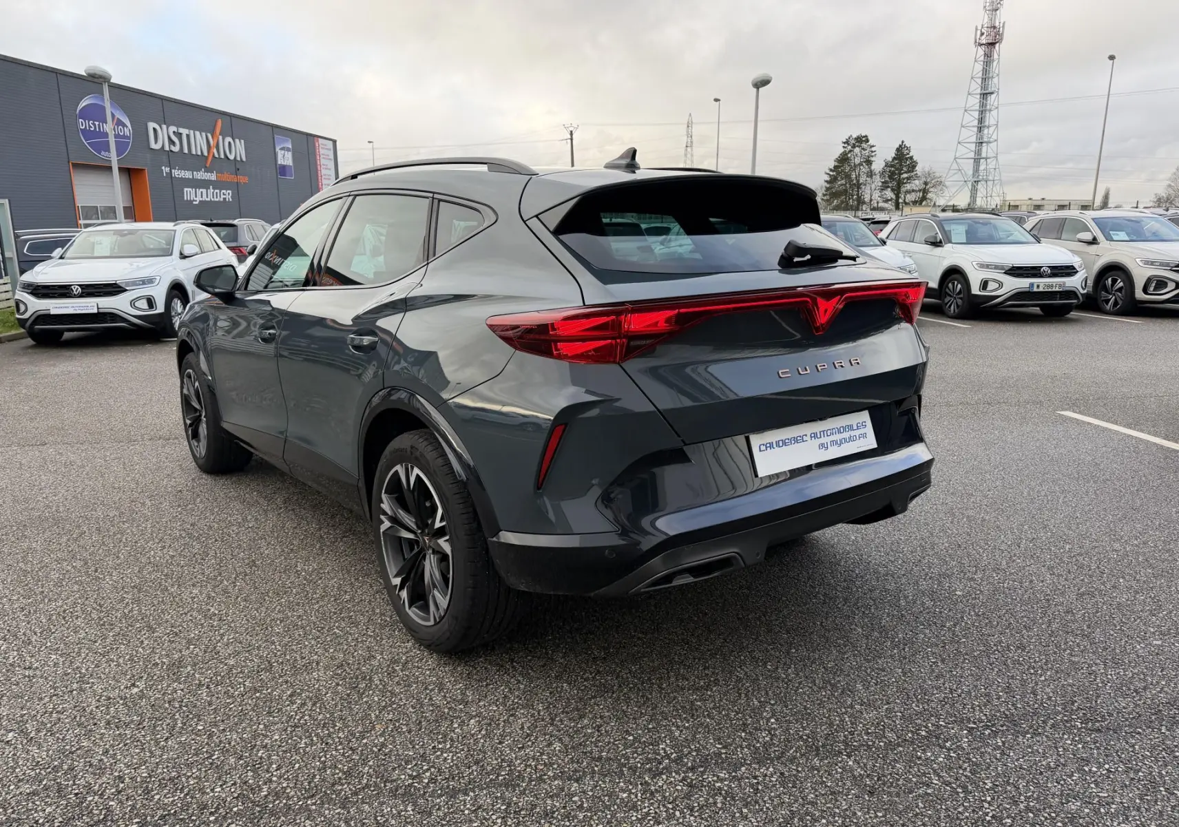 Vue 3/4 arrière droite d'un CUPRA Formentor gris foncé avec feux arrière en bandeau lumineux et double sortie d'échappement.