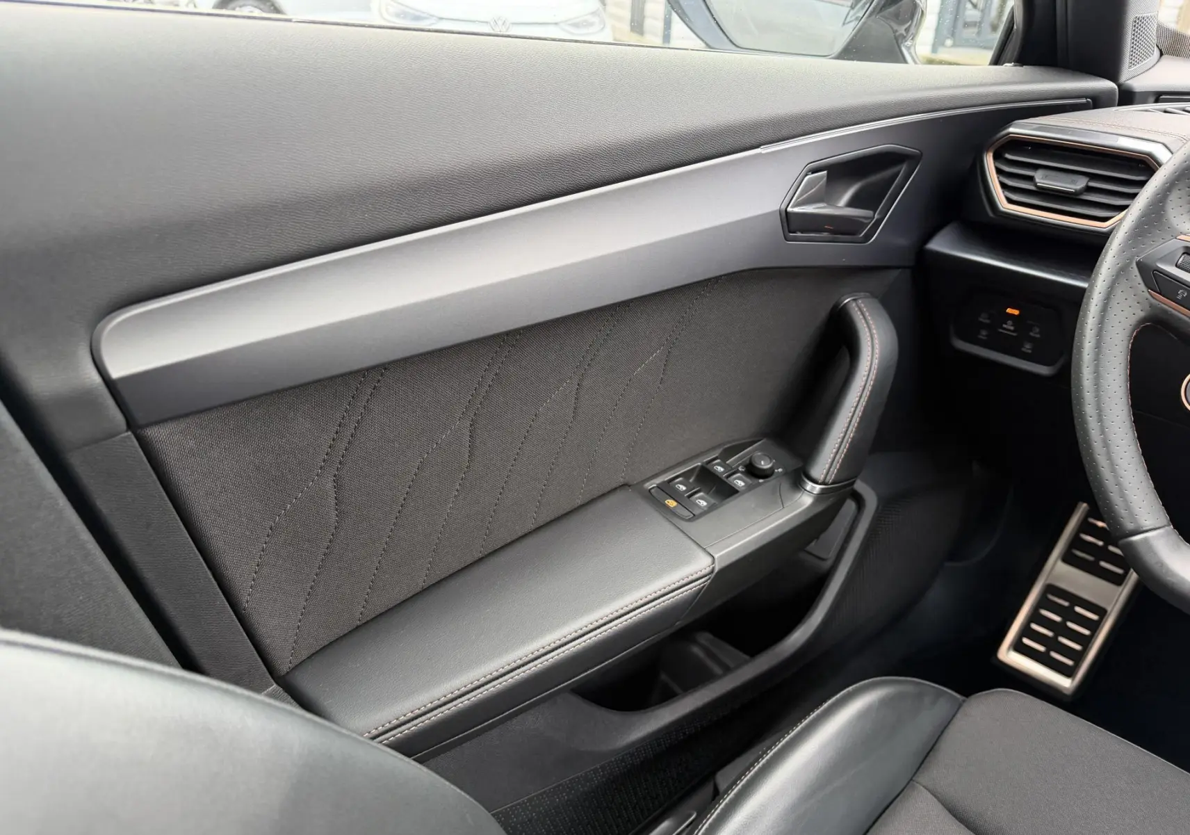 Vue intérieure côté conducteur de la porte noire du CUPRA Formentor avec commandes de vitres et poignée en cuir.