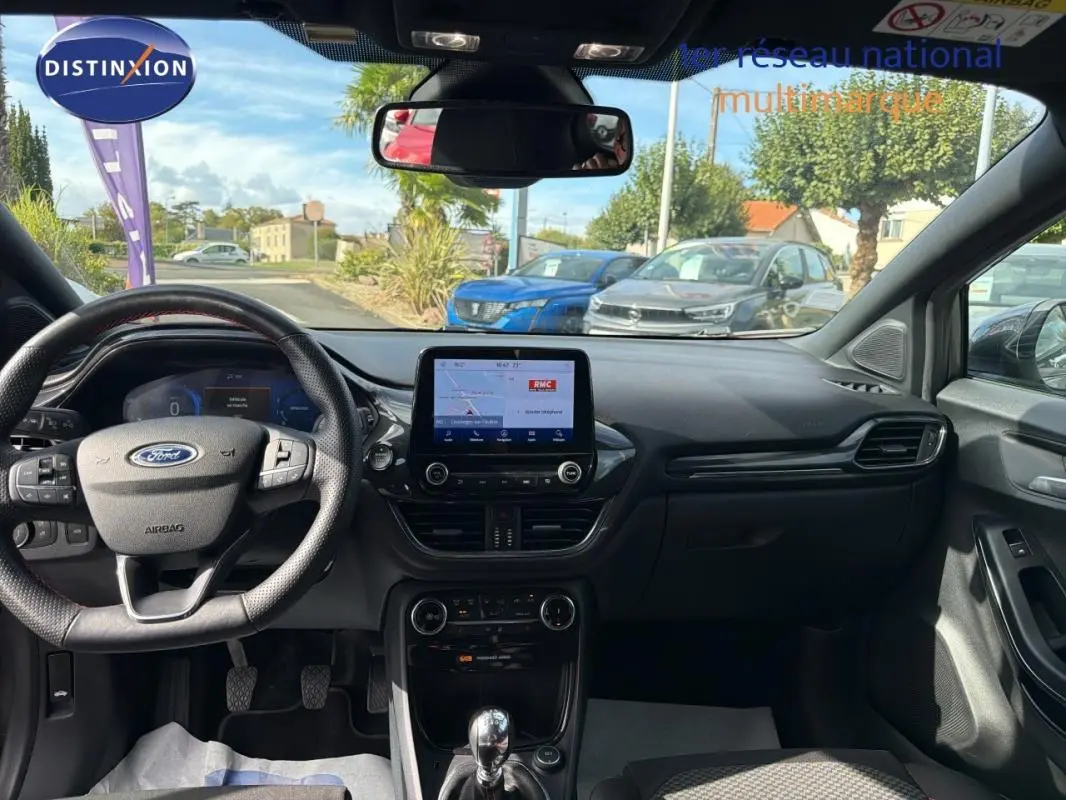 Vue intérieure avant du Ford Puma 2022 gris foncé, avec tableau de bord moderne et écran tactile central allumé.