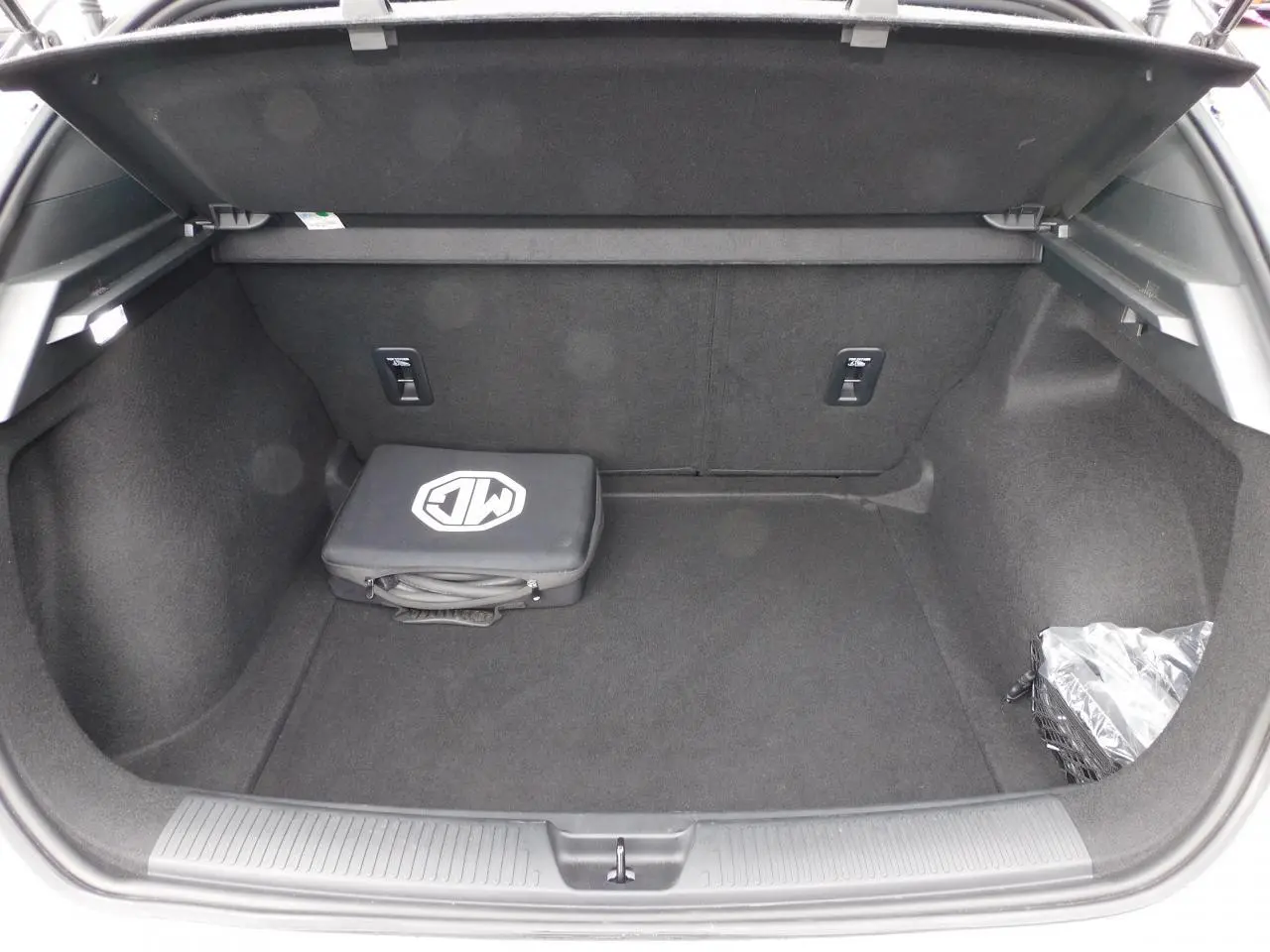 Coffre ouvert d'une MG4 blanche 2023, montrant un sac de recharge noir avec logo MG posé à l'intérieur.