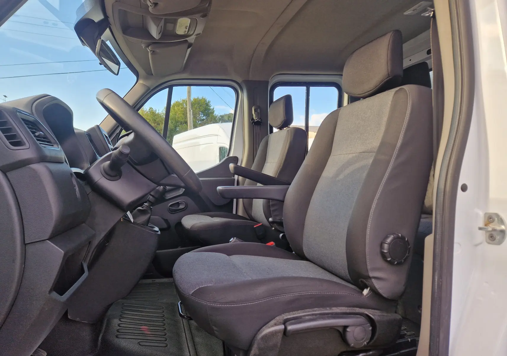 Intérieur du Renault Master Châssis Dble Cab blanc 2023, vue côté gauche sur les sièges avant gris avec accoudoir.