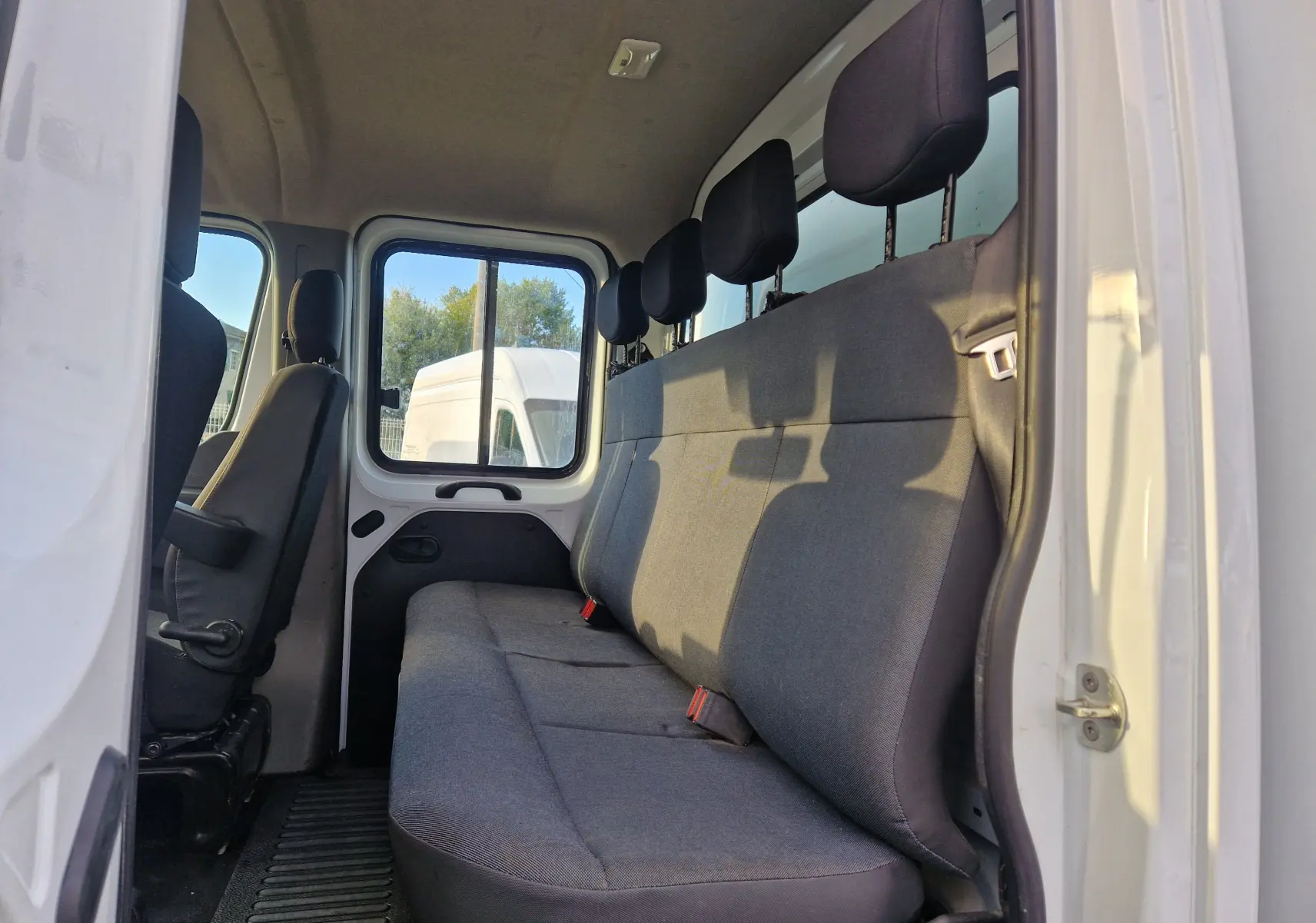 Vue intérieure côté droit de la banquette arrière grise du Renault Master Châssis Double Cabine blanc 2023 avec six places.