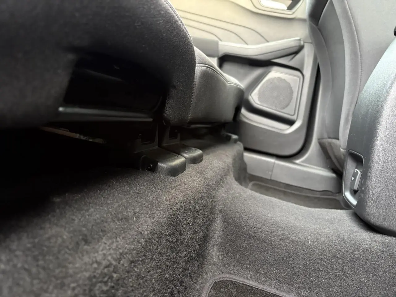Vue rapprochée du plancher arrière côté droit du Ford Kuga 2024 gris Solar, montrant la moquette et la base des sièges.