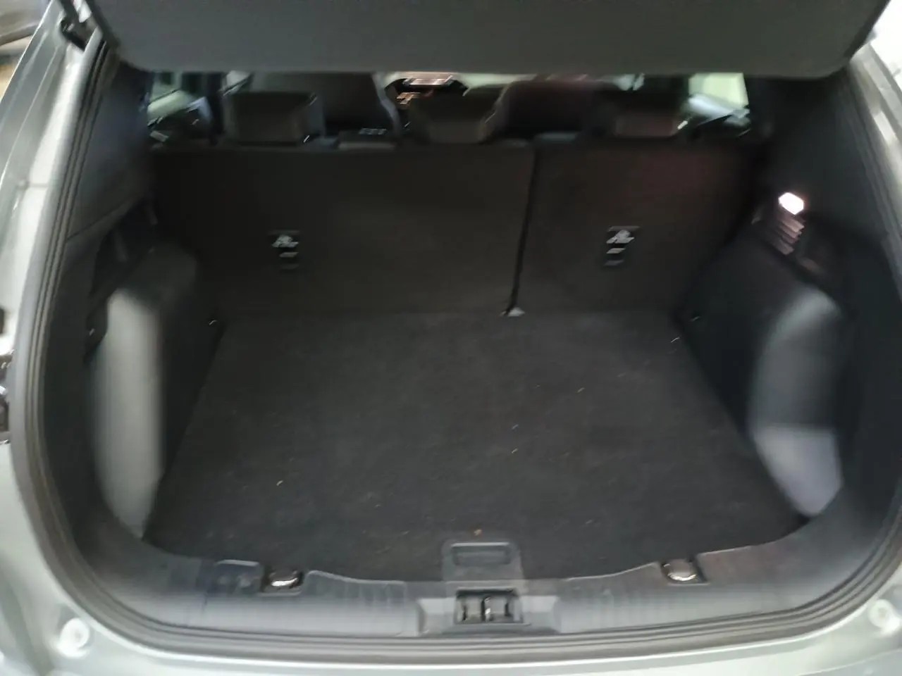 Coffre ouvert du Ford Kuga gris Solar 2024, vue intérieure arrière montrant l'espace de chargement vide.