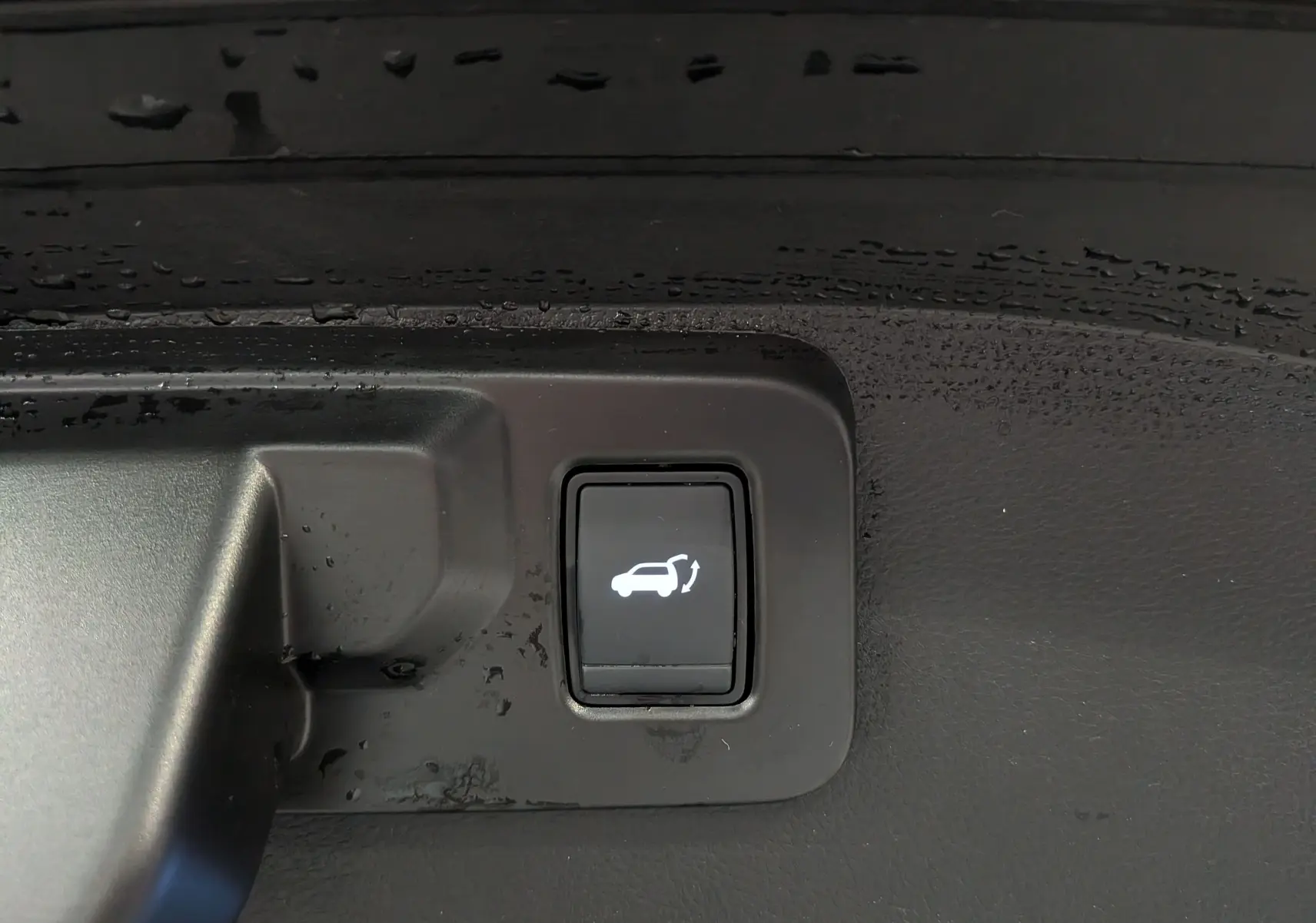 Bouton intérieur noir avec symbole blanc d'ouverture du coffre, sur Renault Austral E-Tech hybrid 2023.