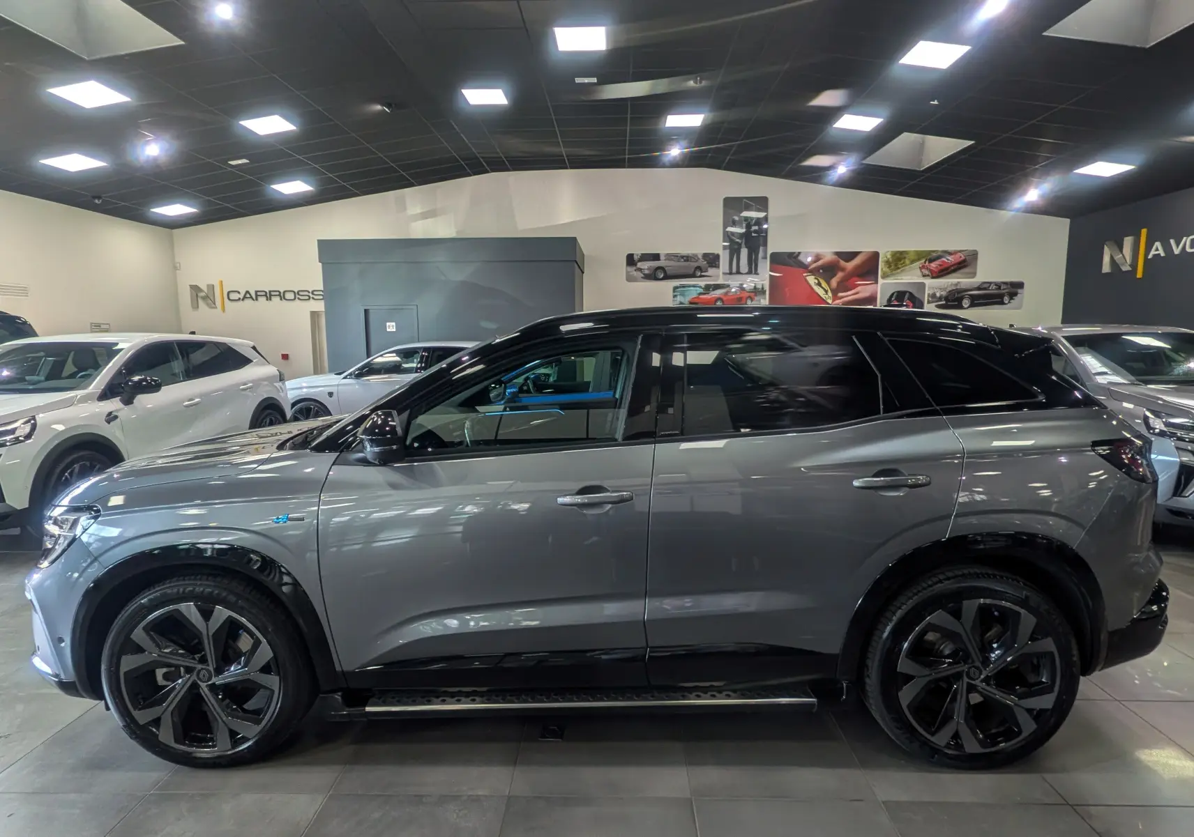 Vue de profil droit du Renault Austral E-Tech hybrid 200 Iconic gris schiste avec toit noir dans un showroom.