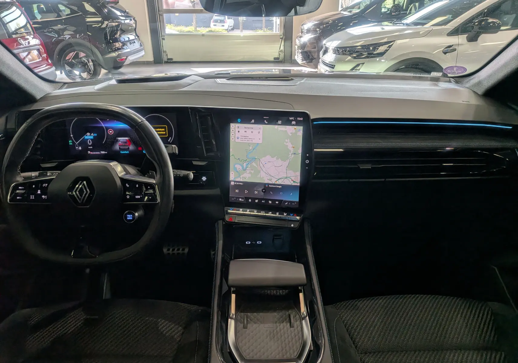 Vue intérieure avant du Renault Austral E-Tech hybride 2023, tableau de bord noir avec écran tactile central vertical et volant multifonction.