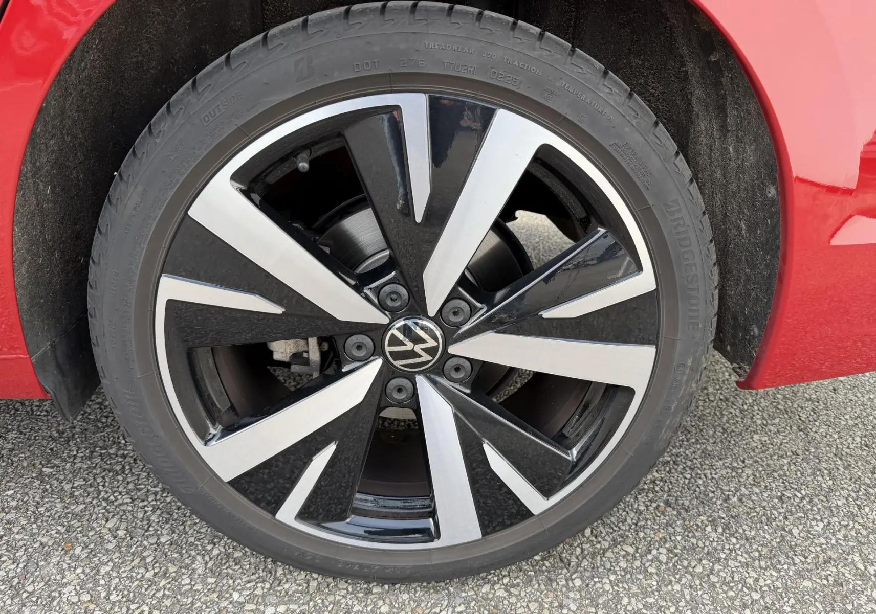 Gros plan sur la jante alliage noir et argent Catania 18 pouces de la Volkswagen Golf SW rouge, côté avant droit.