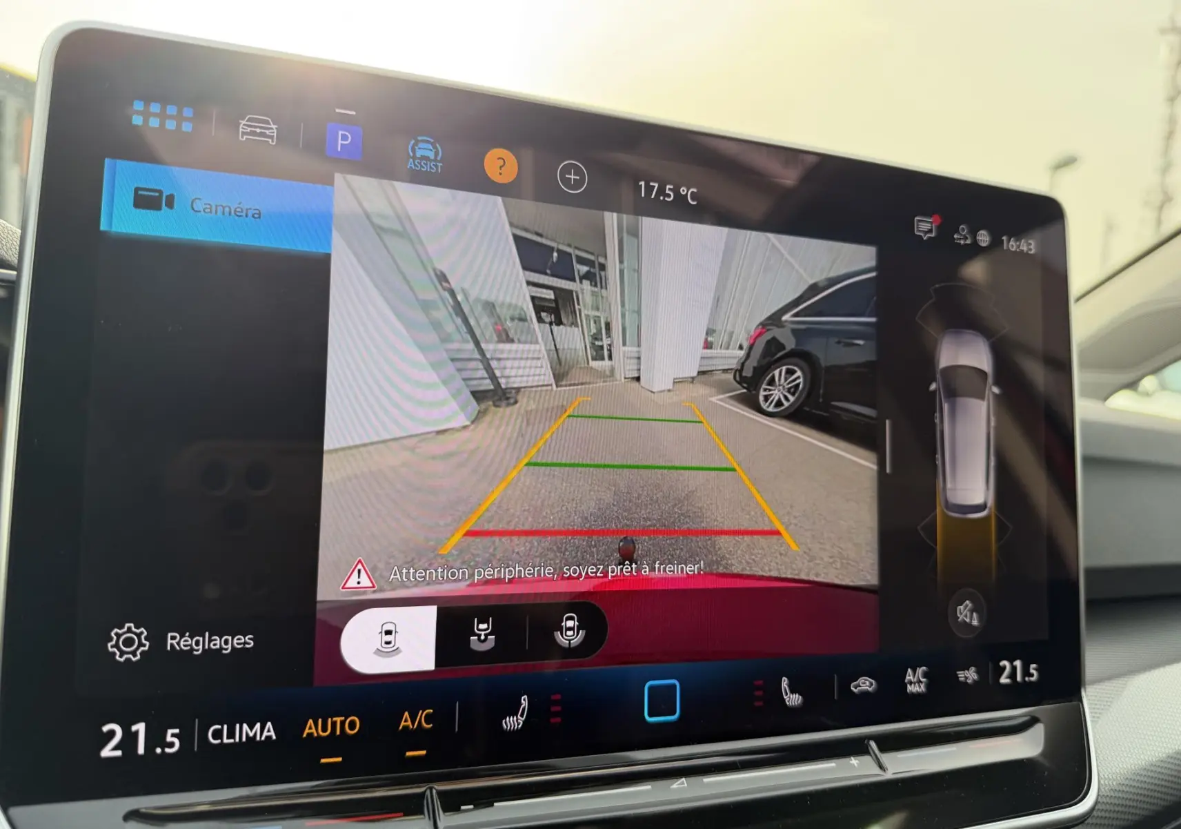 Écran tactile affichant la caméra de recul d'une Volkswagen Golf SW rouge avec lignes de guidage colorées.