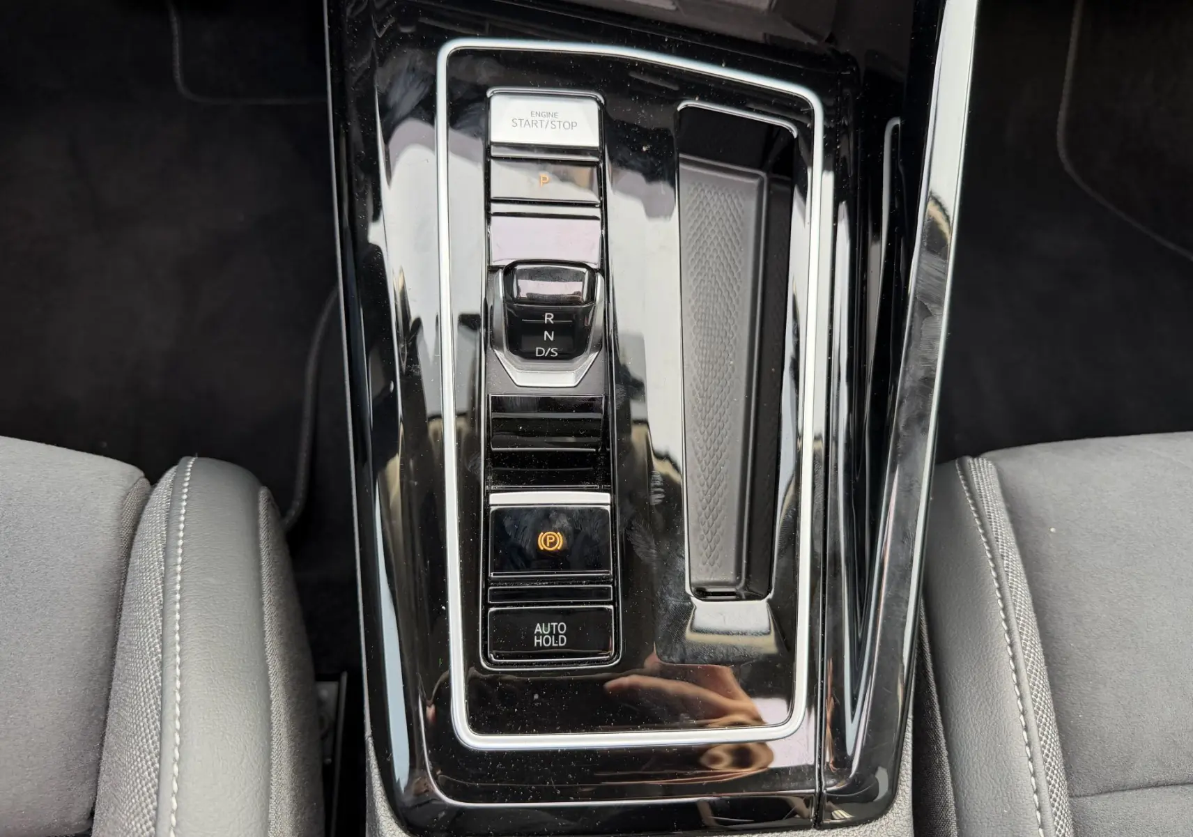 Vue rapprochée de la console centrale noire brillante avec sélecteur de vitesses et commandes électroniques d'une Volkswagen Golf SW.