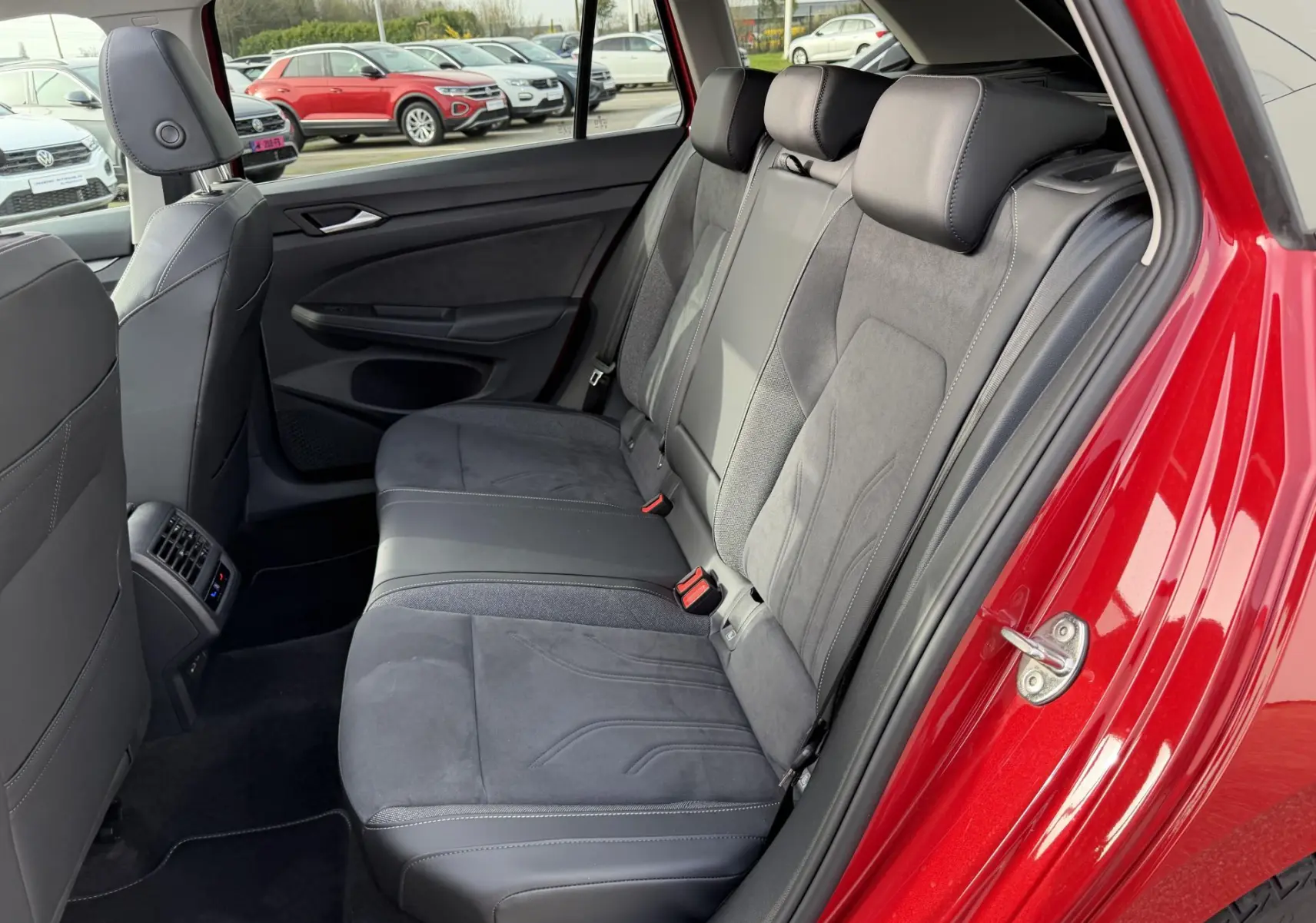 Vue intérieure arrière côté gauche de la Volkswagen Golf SW rouge, montrant les sièges arrière en cuir et alcantara gris.