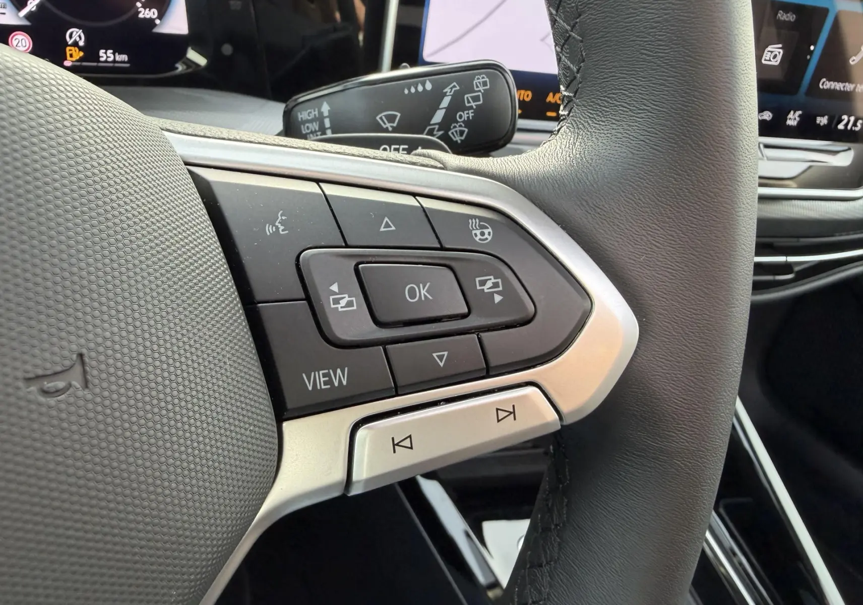 Gros plan sur les commandes multifonctions du volant cuir d'une Volkswagen Golf SW 2.0 TDI 2025, intérieur noir.