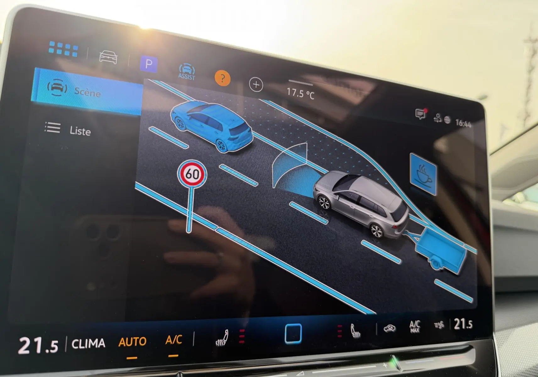 Écran tactile intérieur montrant l’aide au stationnement avec vue 3D d’une Golf SW grise et une remorque, interface moderne.