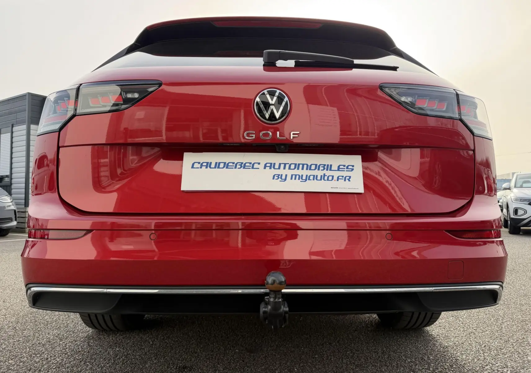 Vue arrière d'une Volkswagen Golf SW rouge avec attelage rabattable et feux Matrix LED visibles.