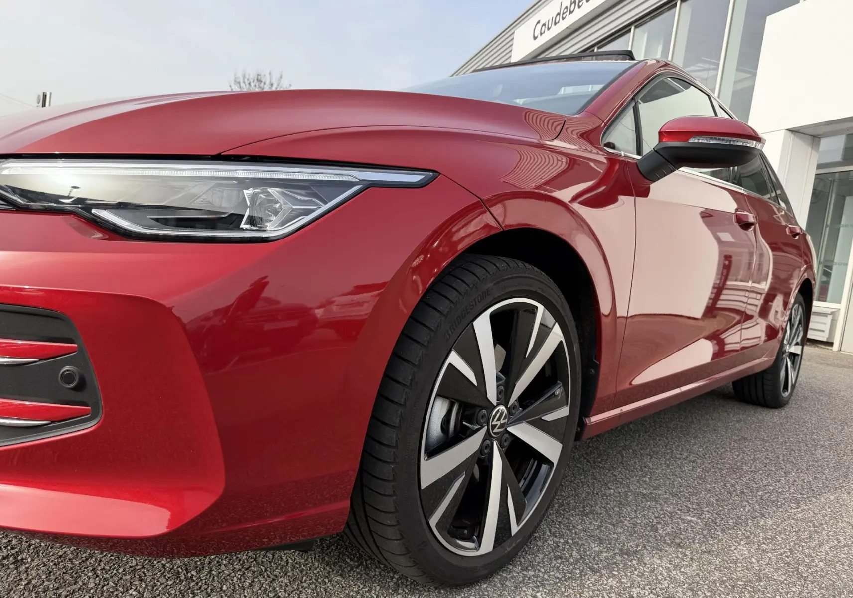 Vue 3/4 avant droit d'une Volkswagen Golf SW rouge métallisée avec jantes alliage noir brillant et projecteurs Matrix LED.