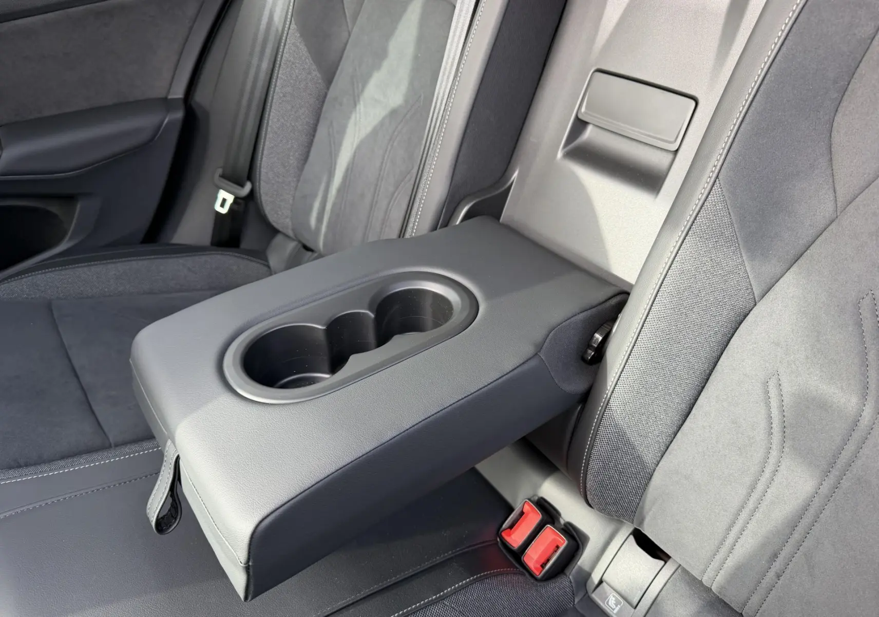 Accoudoir central arrière déployé avec porte-gobelets, sièges tissu gris foncé de la Volkswagen Golf SW 2025.