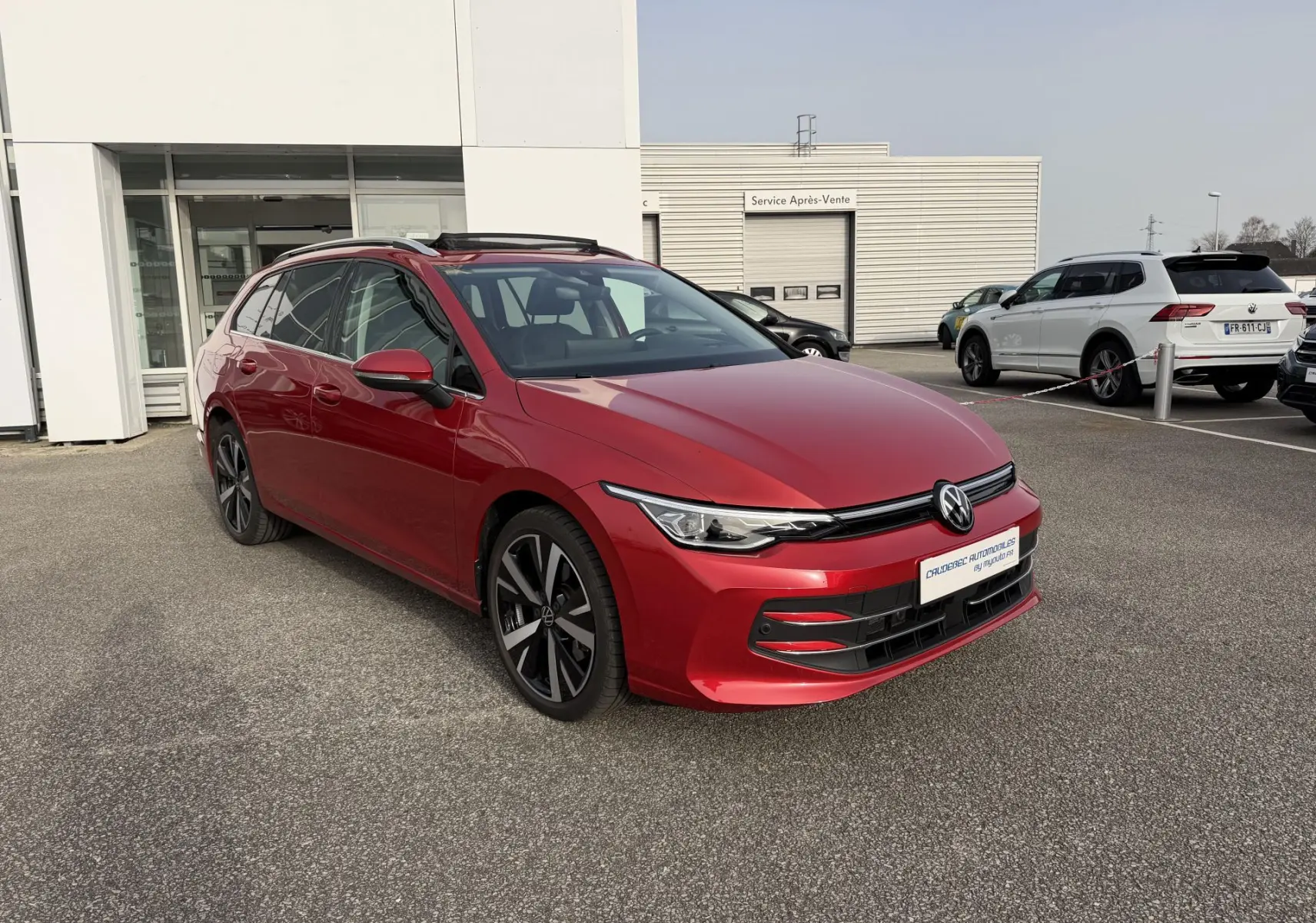 Volkswagen Golf SW rouge vue 3/4 avant gauche, avec jantes alliage noir brillant et toit ouvrant panoramique.