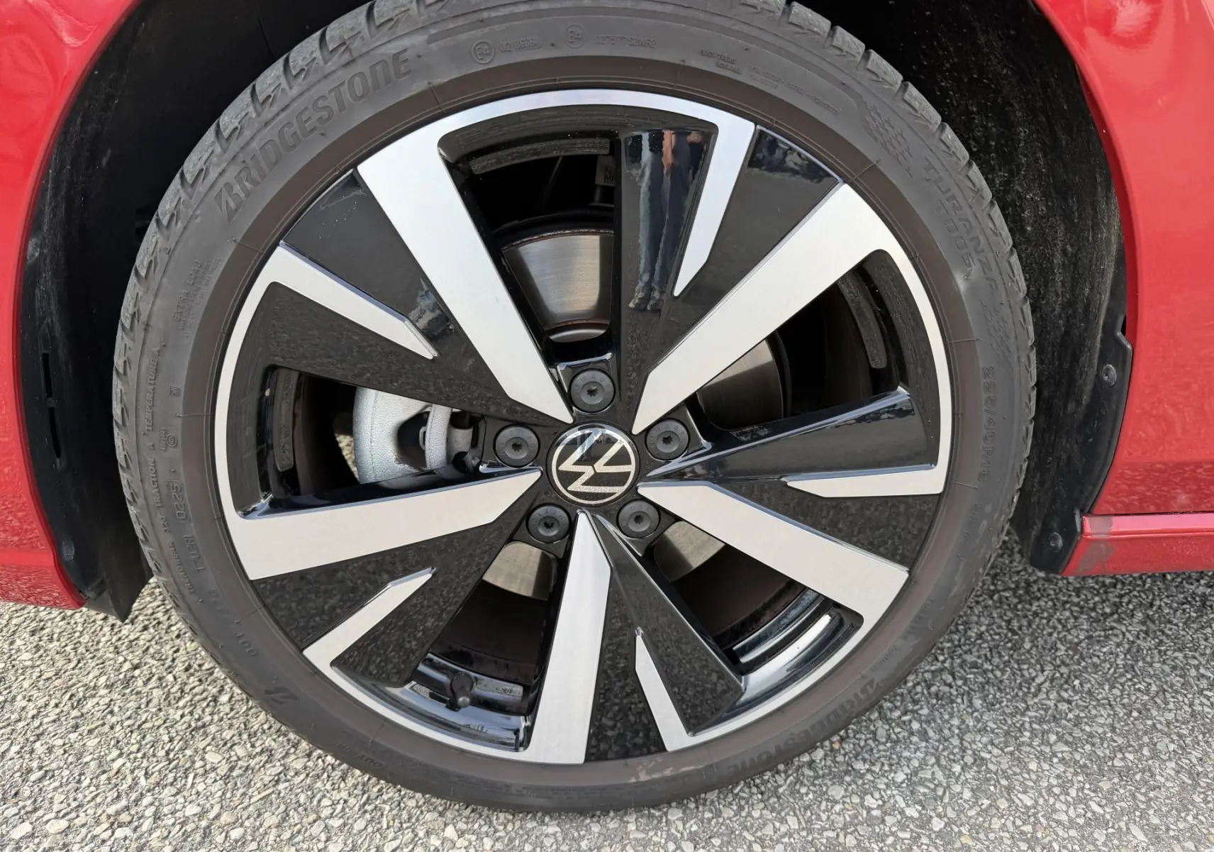 Gros plan sur la jante alliage noir et argent Catania 18 pouces de la Volkswagen Golf SW rouge, avec pneu Bridgestone.