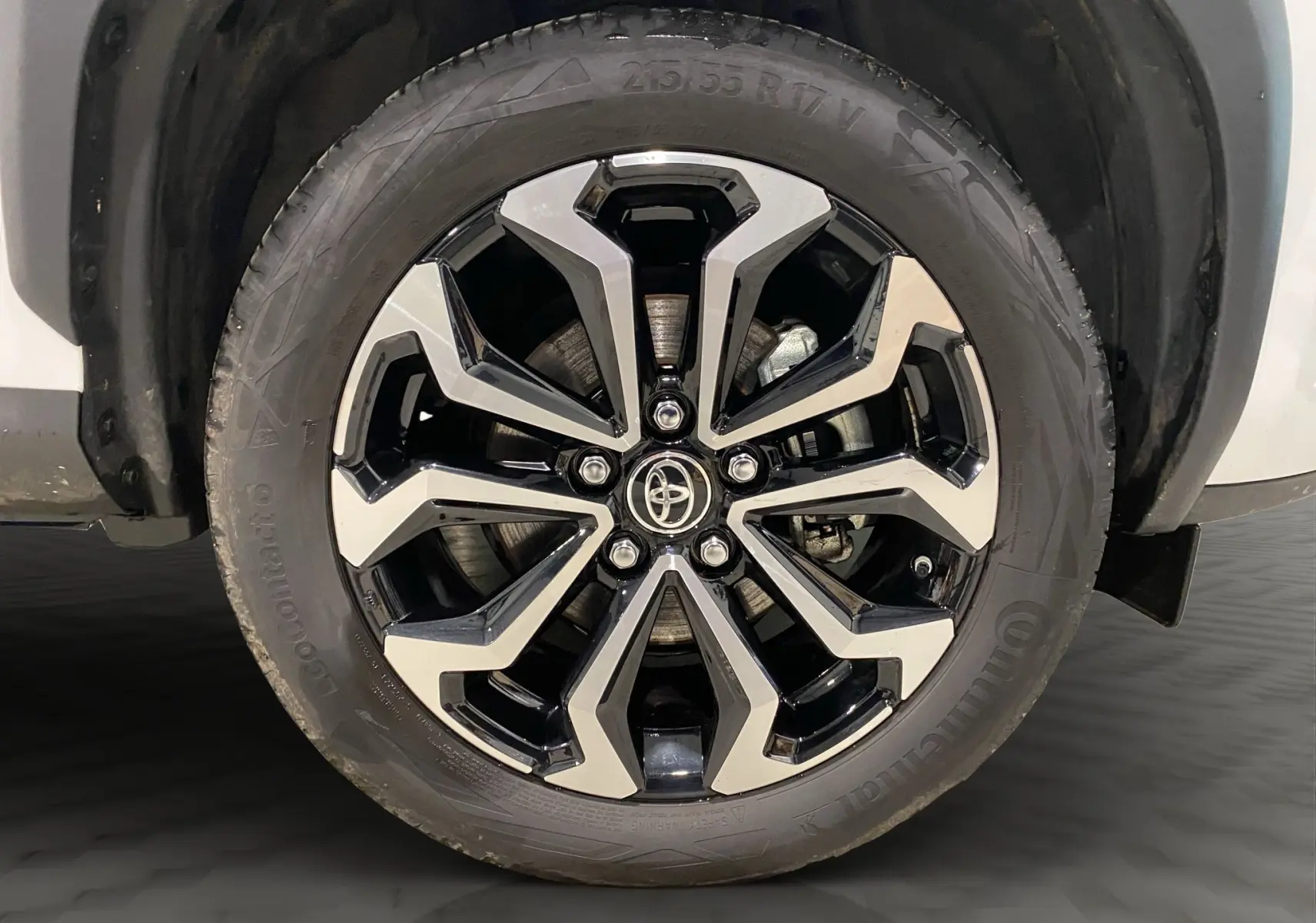 Gros plan sur la jante alu 17 pouces bicolore noir et argent de la roue avant droite d'une Toyota Yaris Cross blanche.