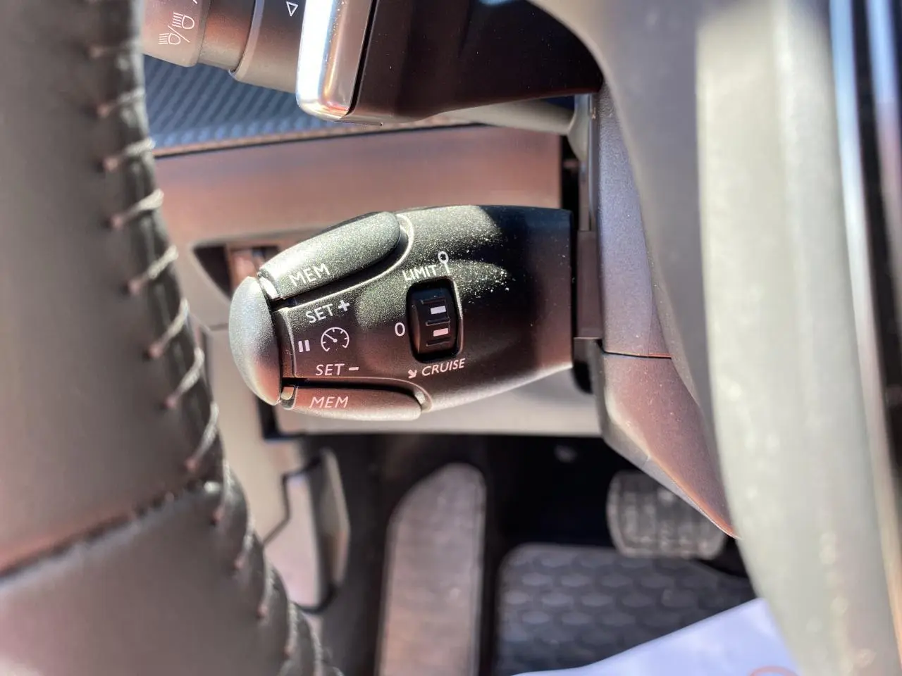 Gros plan sur la commande de régulateur de vitesse du Peugeot 2008 2021, côté gauche du volant en cuir noir.