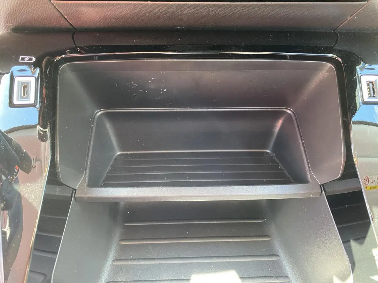 Gros plan sur la console centrale noire du Peugeot 2008 2021, avec prises USB et finition brillante autour.