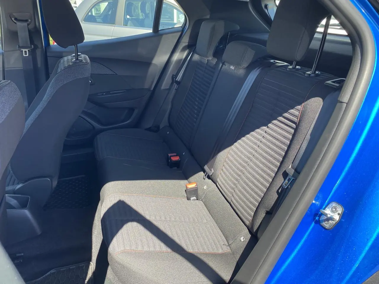 Vue intérieure arrière côté droit du Peugeot 2008 bleu Vertigo, montrant les sièges arrière en tissu noir avec surpiqûres.