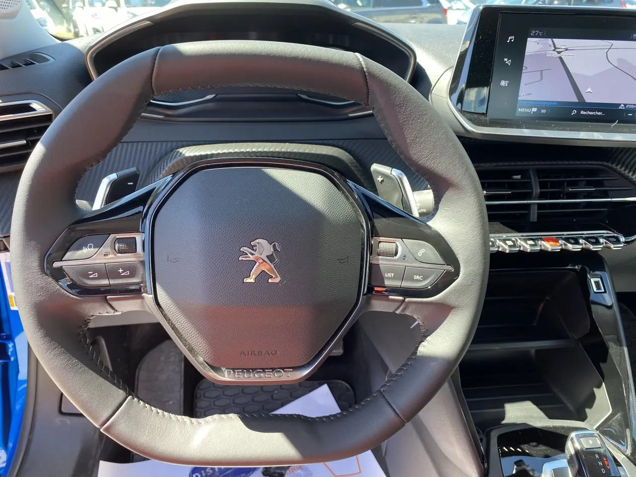 Vue rapprochée du volant cuir noir et du tableau de bord avec écran tactile du Peugeot 2008 bleu Vertigo 2021.