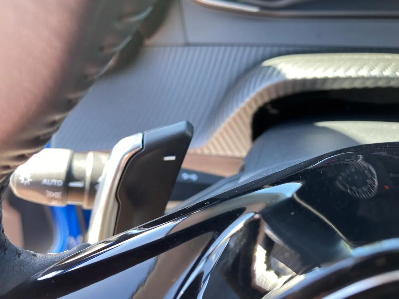 Gros plan sur la palette de changement de vitesses côté gauche du volant d’un Peugeot 2008 bleu Vertigo.