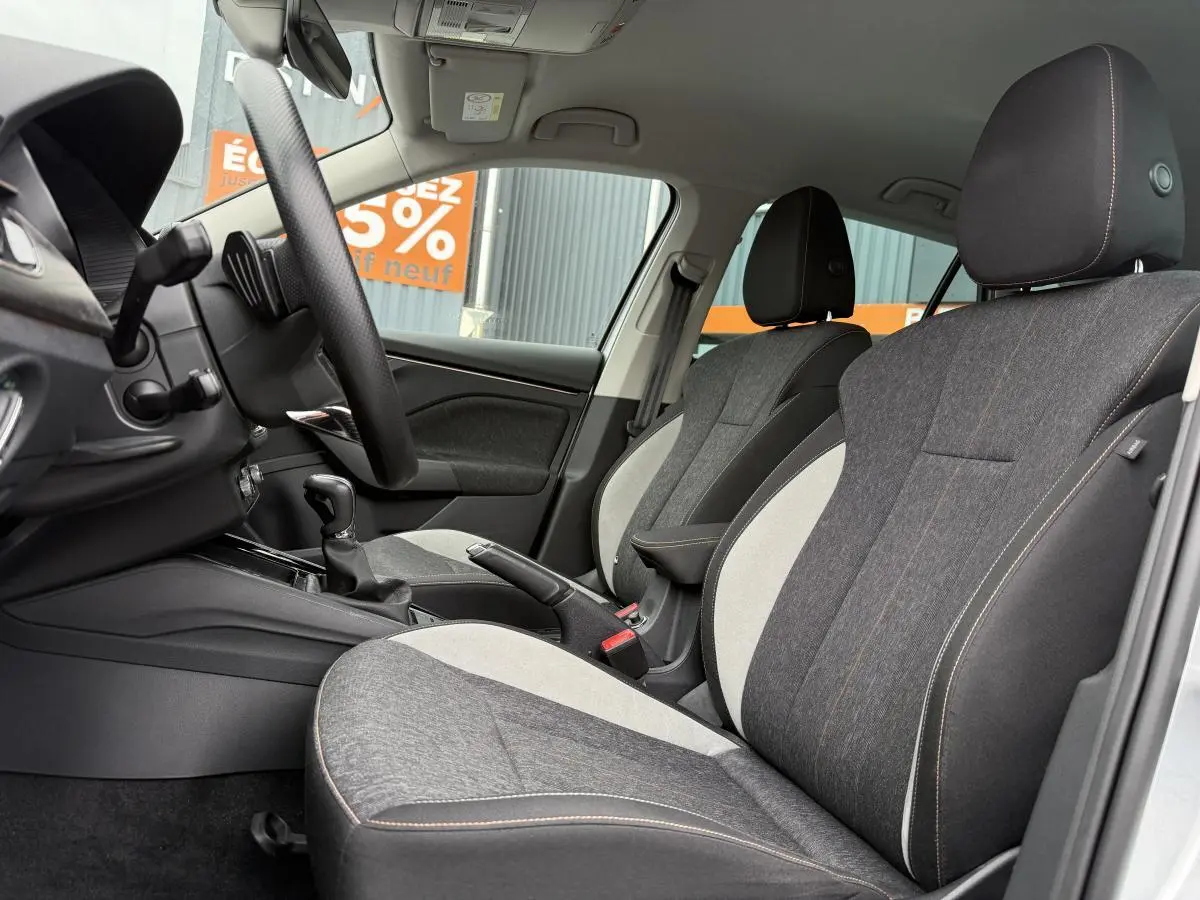 Intérieur avant du Skoda Kamiq 2022, sièges tissu bicolore gris et noir avec surpiqûres orange visibles côté conducteur.
