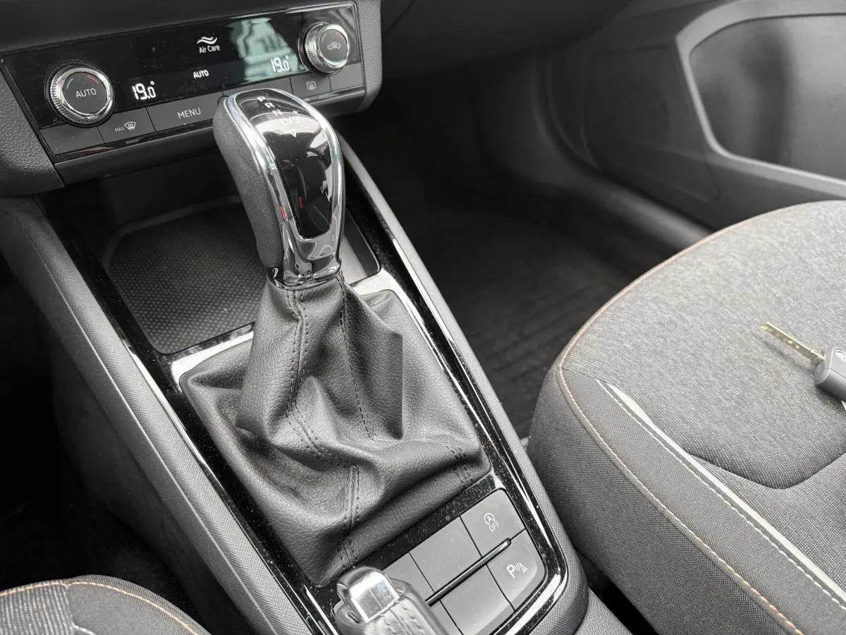 Gros plan sur la console centrale intérieure du Skoda Kamiq 2022 avec levier de vitesses automatique et sièges tissu gris.
