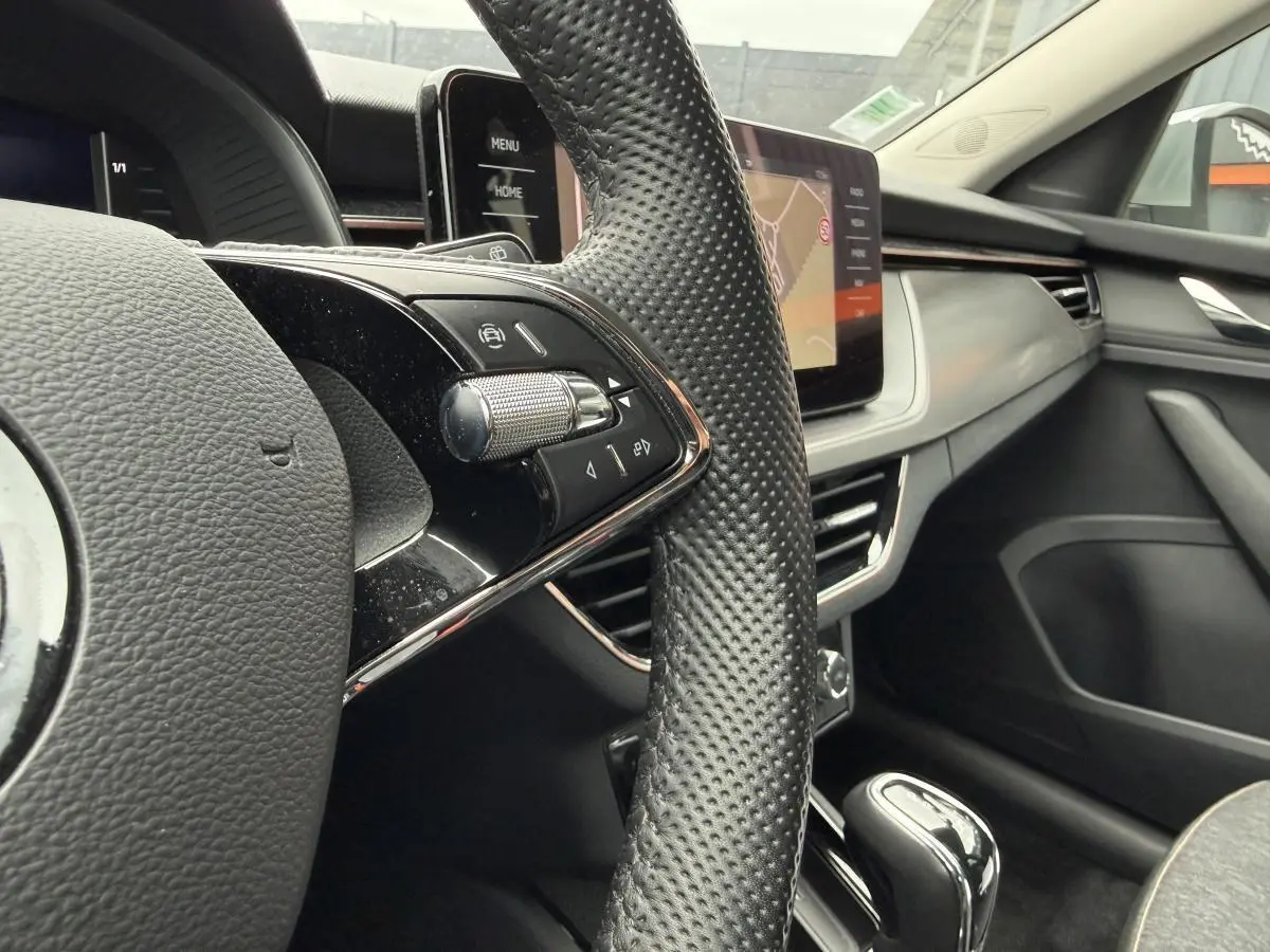 Gros plan sur le volant et la console centrale du Skoda Kamiq gris, avec écran tactile et commandes intégrées.