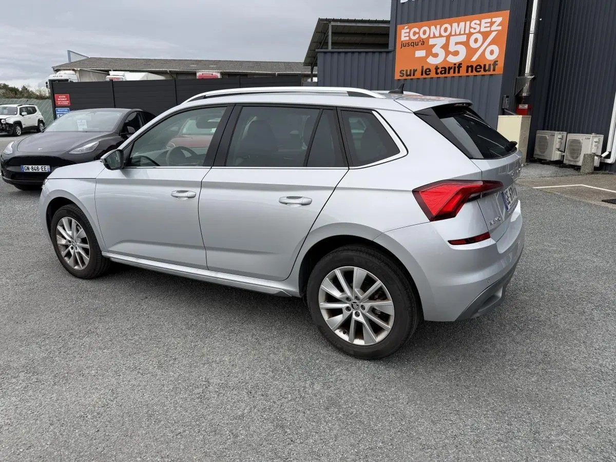 Vue 3/4 arrière droite d'un Skoda Kamiq gris métallisé garé sur un parking avec jantes alliage 17 pouces.