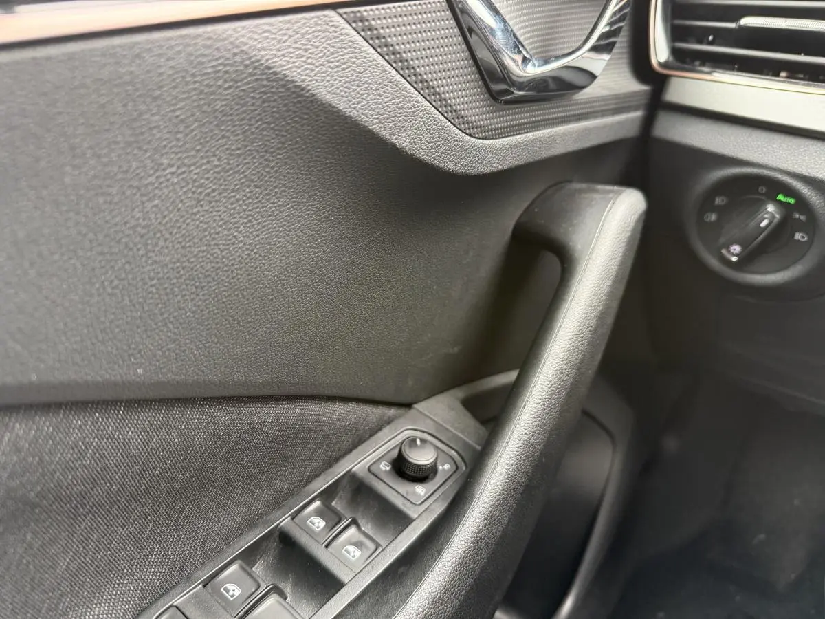 Détail de la porte côté gauche du Skoda Kamiq gris 2022, avec commandes des vitres et réglage des rétroviseurs.