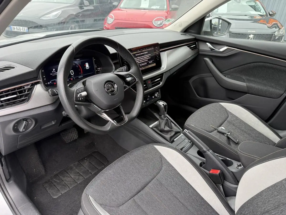 Intérieur du Skoda Kamiq 2022 vu côté conducteur, sièges tissu gris et console centrale avec boîte auto DSG7.