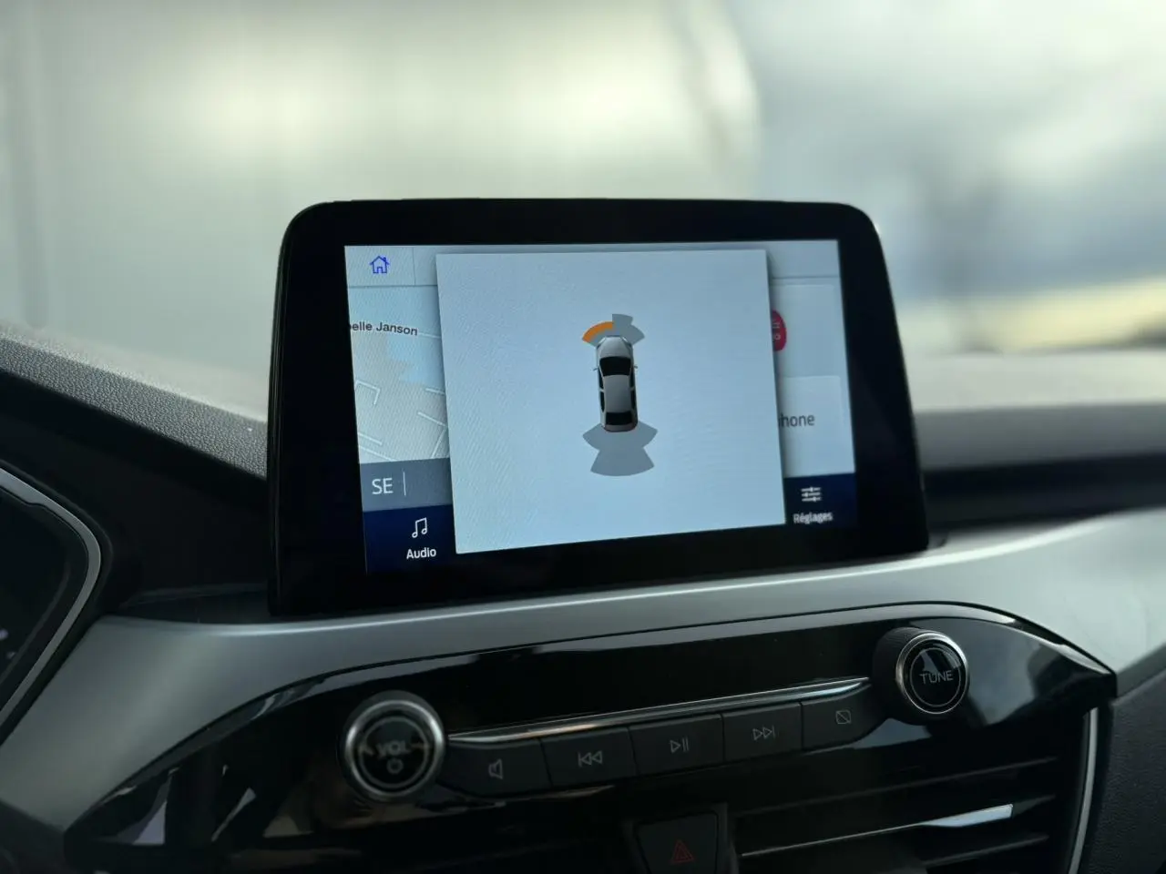 Écran tactile central du Ford Kuga 2024 affichant l'aide au stationnement, vue intérieure du tableau de bord.