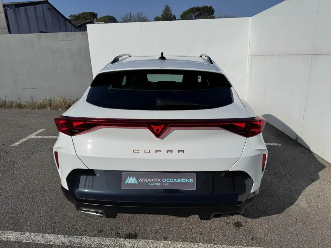 Vue arrière d'un CUPRA Formentor blanc nacré avec toit noir et bandeau lumineux rouge intégrant le logo CUPRA.