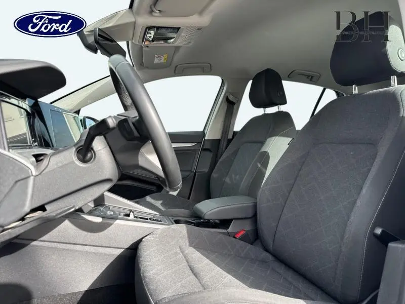 Vue intérieure côté conducteur de la Volkswagen Golf gris lunaire 2023, sièges tissu Maze Noir Soul et volant cuir multifonction.