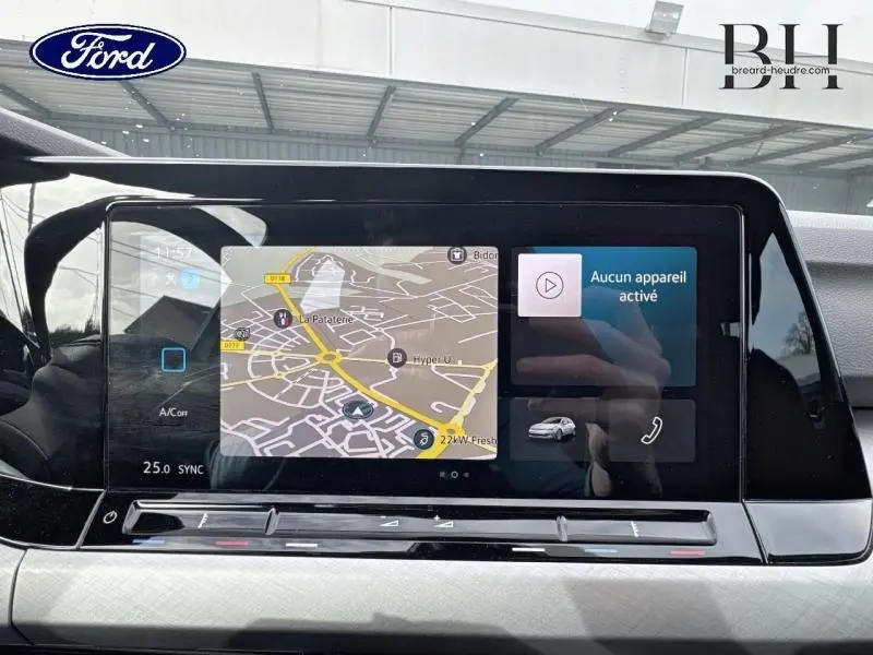 Écran tactile central affichant la navigation et les options multimédias dans une Volkswagen Golf gris lunaire, vue de face.