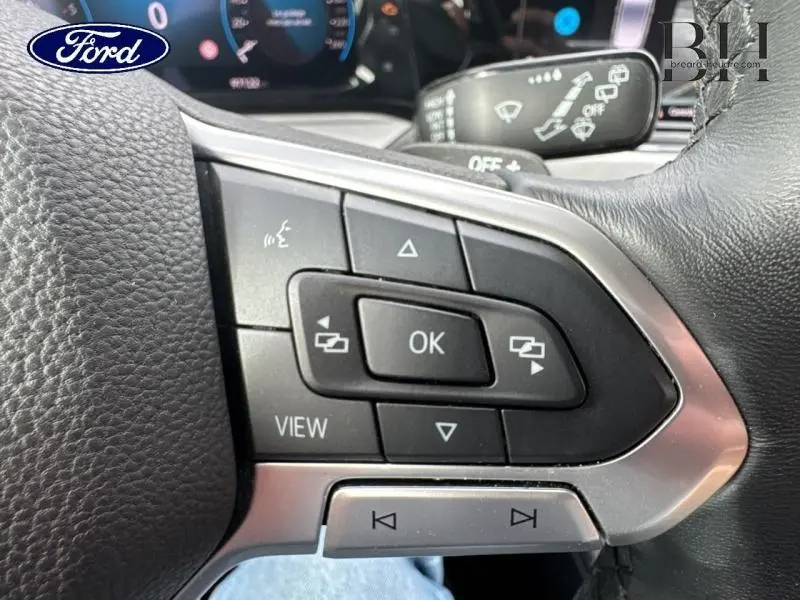 Gros plan sur les commandes multifonctions à droite du volant cuir noir d'une Volkswagen Golf gris lunaire 2023.