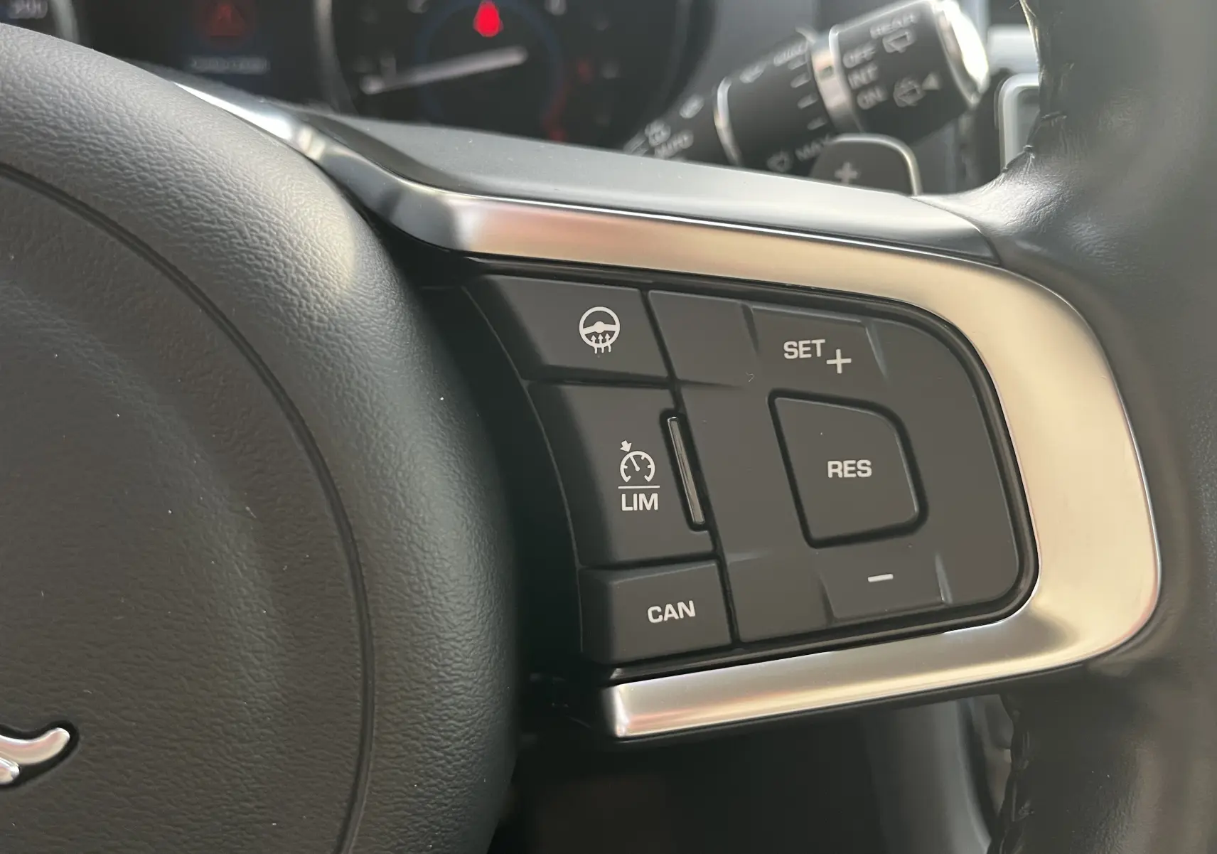 Gros plan sur les commandes de régulateur de vitesse au volant cuir noir du Jaguar F-PACE blanc 2018.