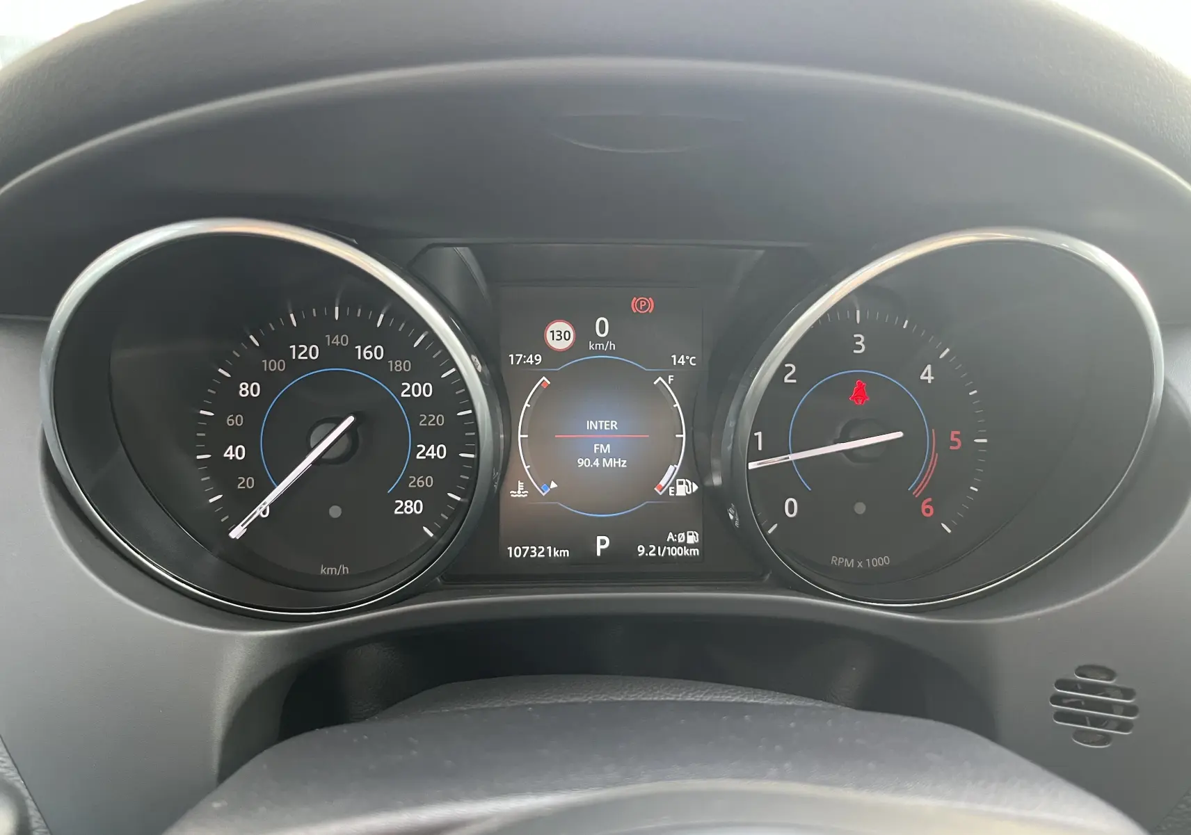 Vue rapprochée du tableau de bord du Jaguar F-PACE blanc 2018, affichant la vitesse, le régime moteur et l'écran central numérique.