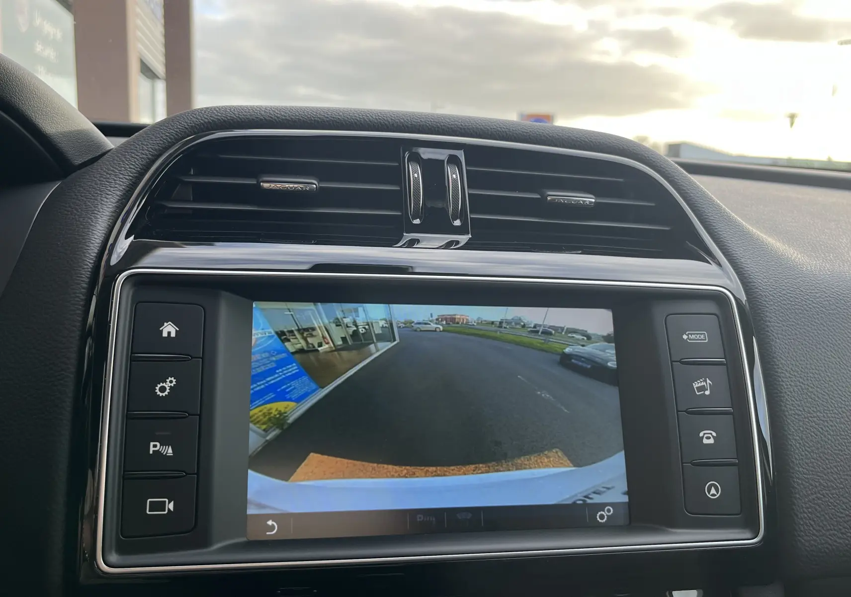 Vue intérieure du tableau de bord du Jaguar F-PACE blanc 2018, avec écran de caméra de recul affiché.