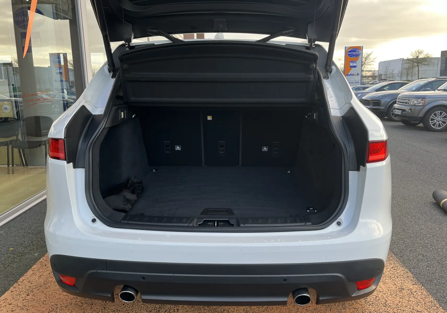 Vue arrière du coffre ouvert du Jaguar F-PACE blanc 2018, mettant en valeur son espace de chargement spacieux.