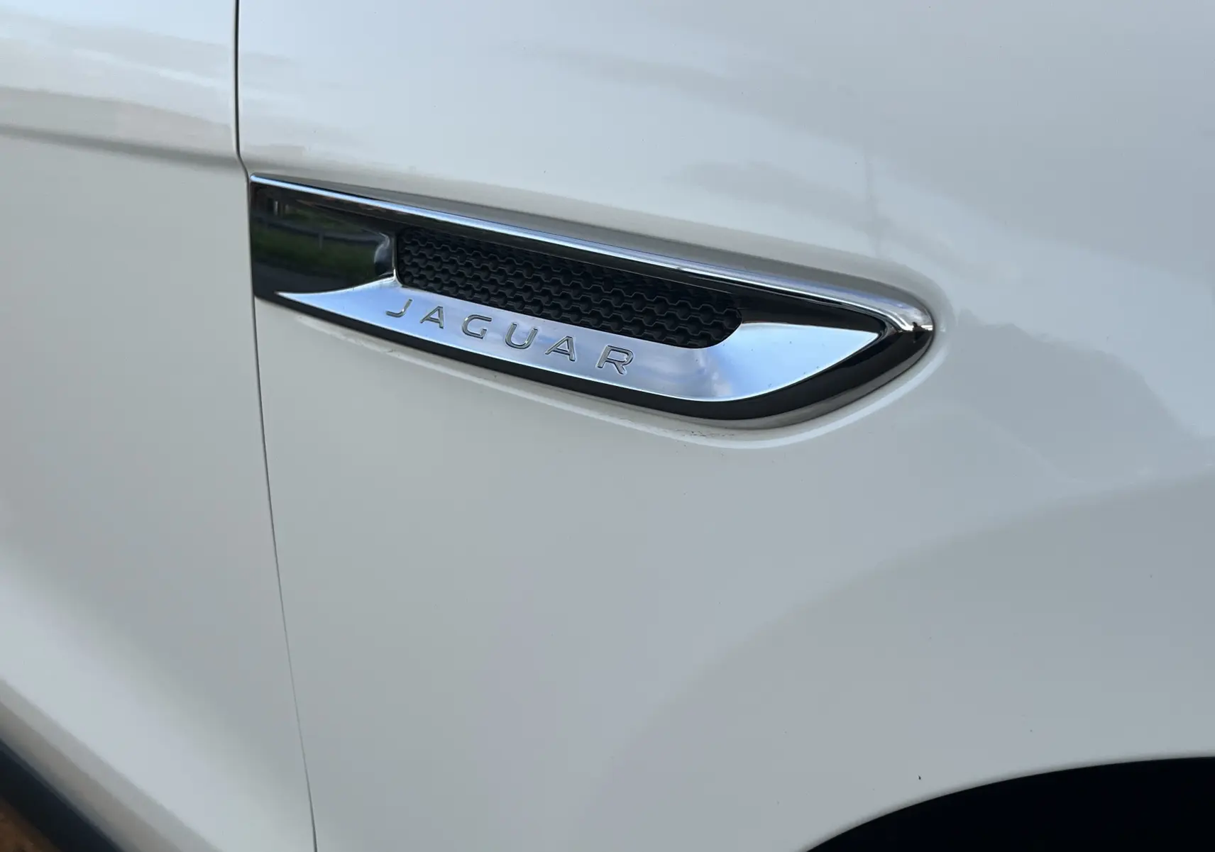 Gros plan sur la prise d'air latérale chromée avec logo Jaguar sur la carrosserie blanche du F-PACE 2018.
