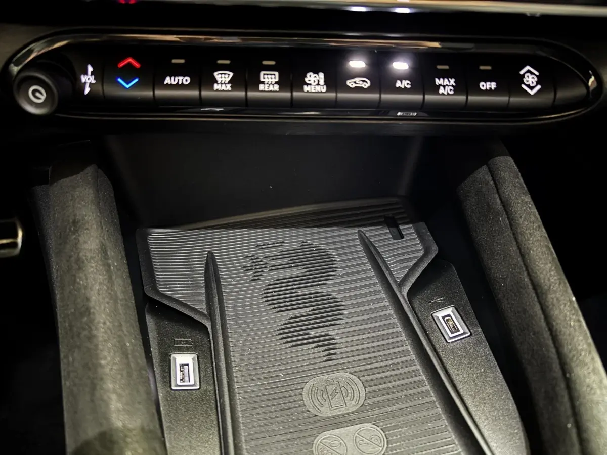 Gros plan sur la console centrale de l'Alfa Romeo Junior 2024, montrant la zone de recharge sans fil avec logo serpent.